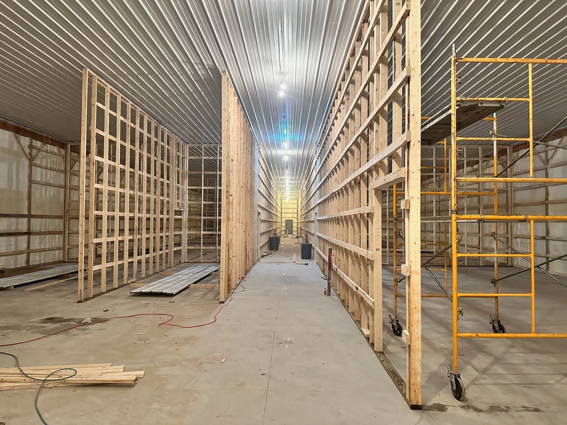 Wood-framed interior under construction with scaffolding and a central walkway