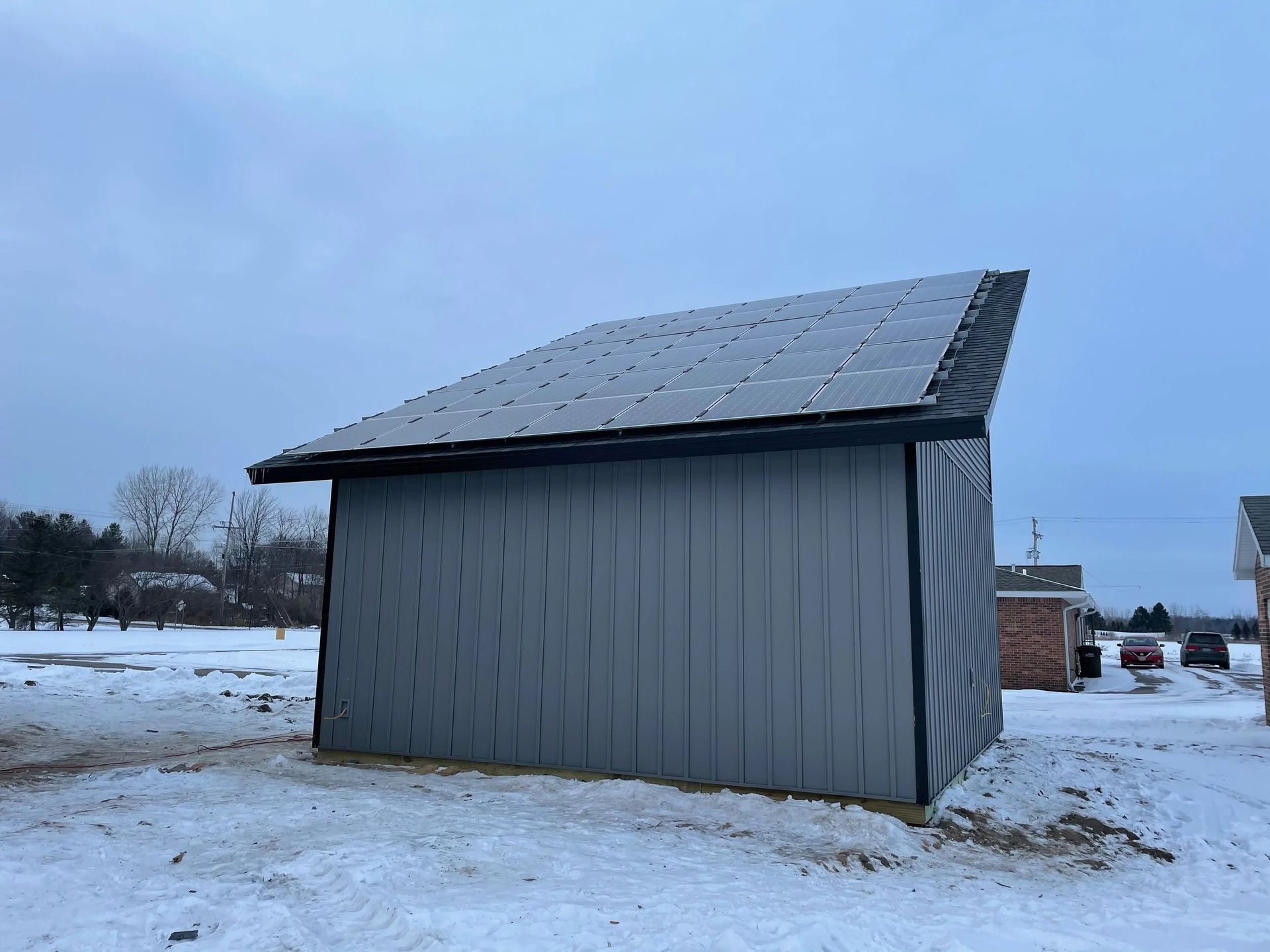 Snow-covered shed with a slanted roof in a wintry field under a cloudy sky