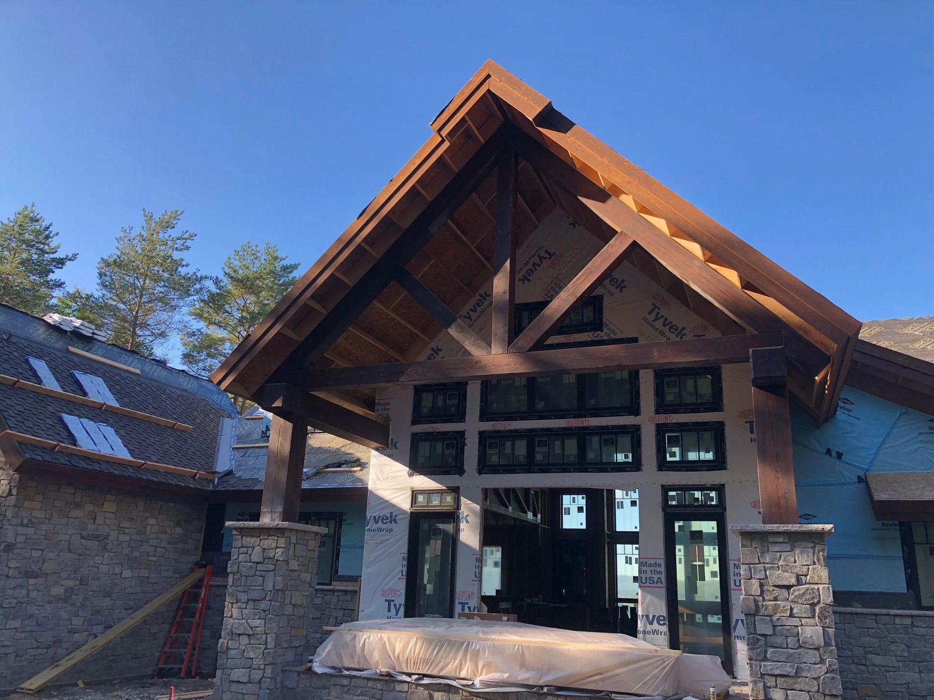 Stone and wood lodge entrance with a peaked roof and large glass doors under a blue sky