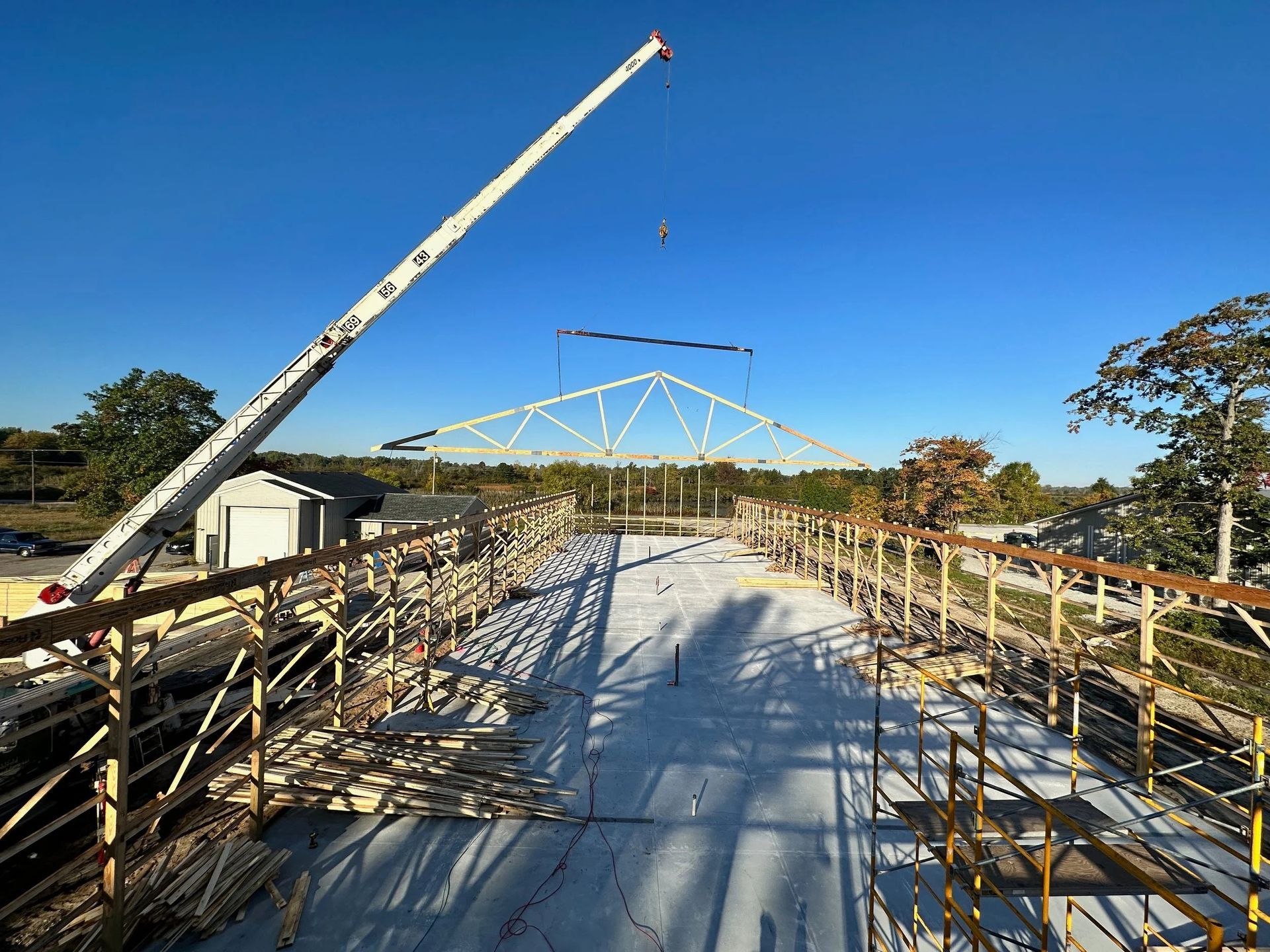 Bridge under construction with crane, scaffolding, and blue sky over a river or wetland
