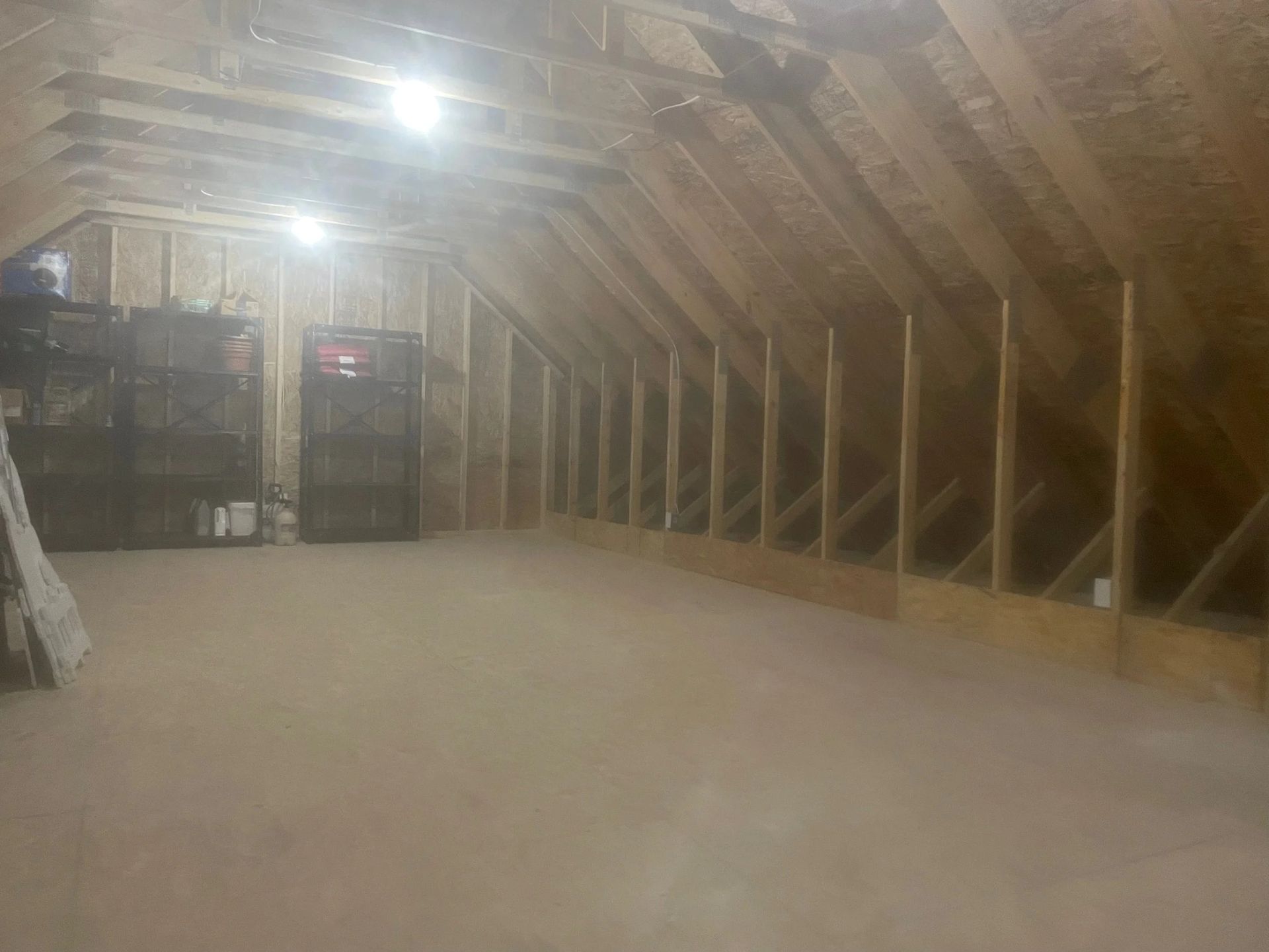 Dim attic with exposed wooden rafters, slanted walls, and a bare floor.
