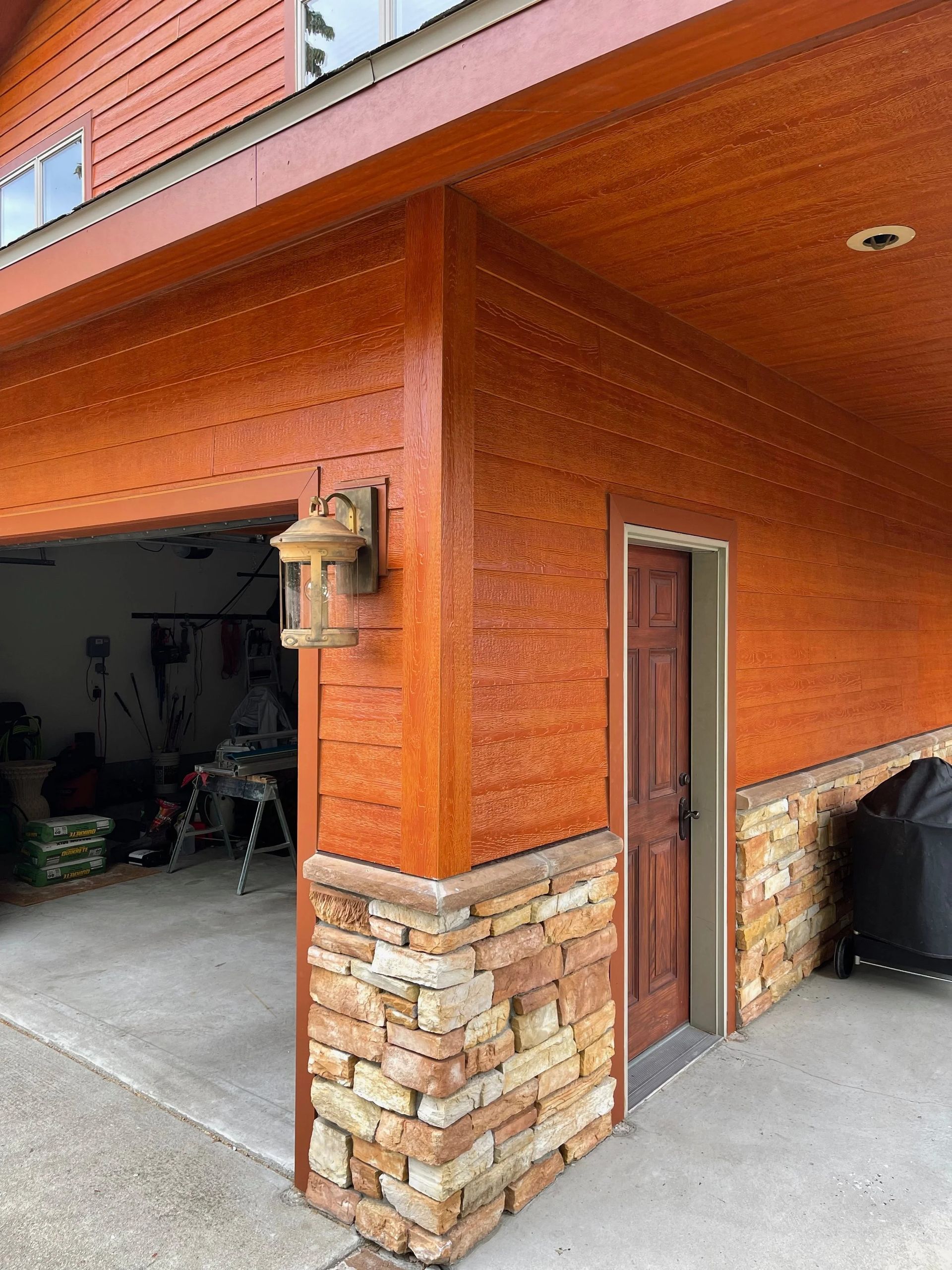Orange stucco garage corner with a side door, brick base, and open garage interior visible