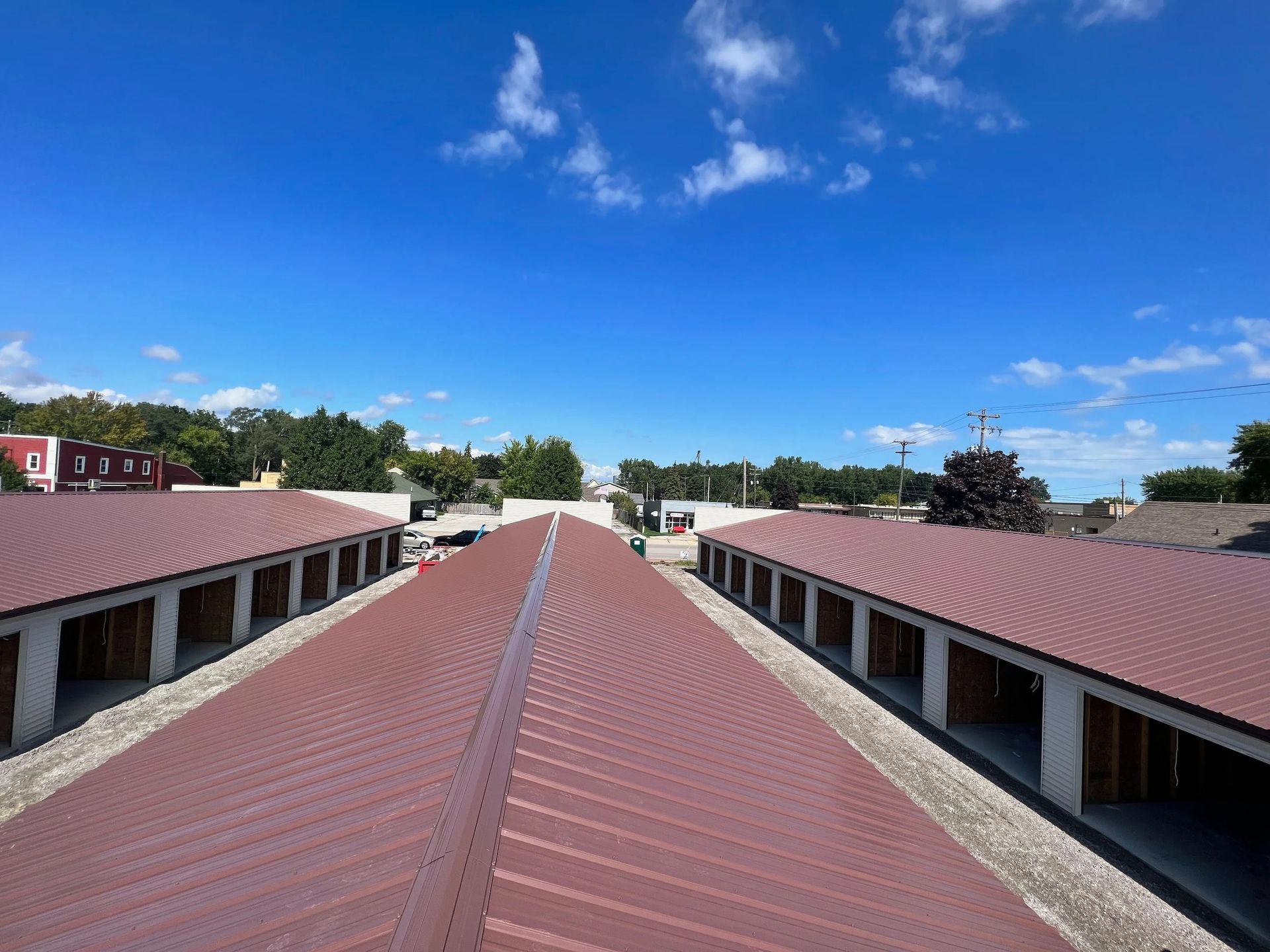 Long red-roofed building complex under a bright blue sky with scattered clouds.
