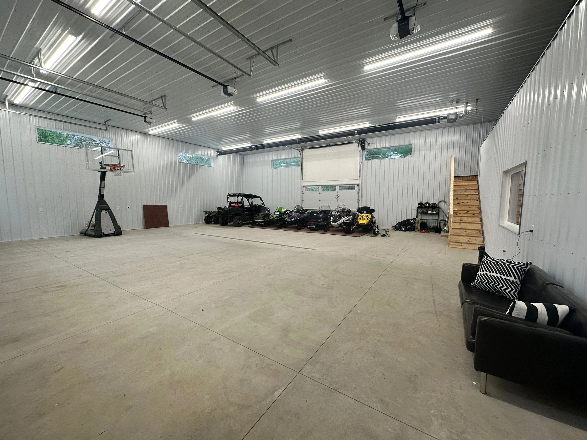Empty white warehouse with overhead lights, concrete floor, and a few items along the walls