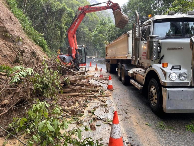 A Large Truck is Driving Down a Road Next to a Large Excavator — Advanced Civil Earthworks In Koah, QLD