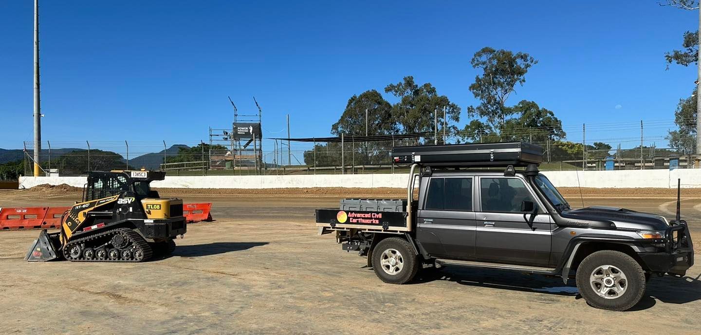 A Truck is Towing a Bulldozer in a Dirt Field — Advanced Civil Earthworks In Mount Isa, QLD