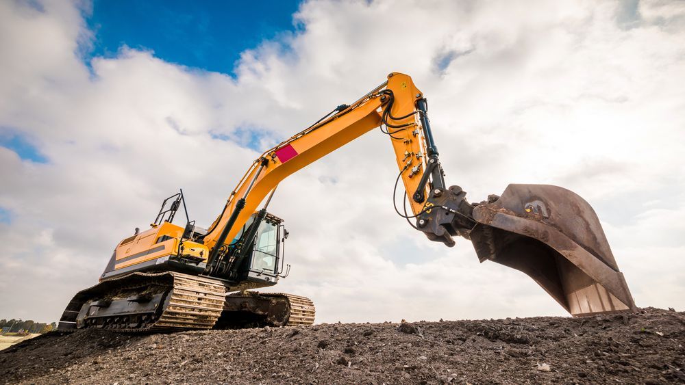 A Large Excavator is Digging a Hole in the Dirt on a Construction Site — Advanced Civil Earthworks In Cassowary Coast, QLD