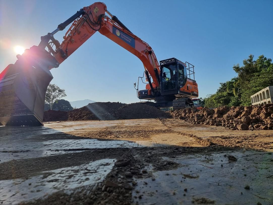 A Large Orange Excavator is Digging a Hole in the Dirt — Advanced Civil Earthworks In Cairns, QLD
