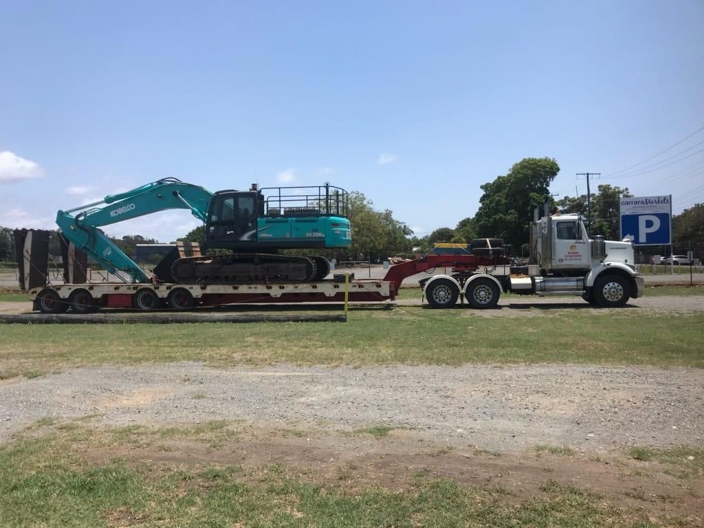 A Large Excavator is Being Towed by a Semi Truck — Advanced Civil Earthworks In Port Douglas, QLD