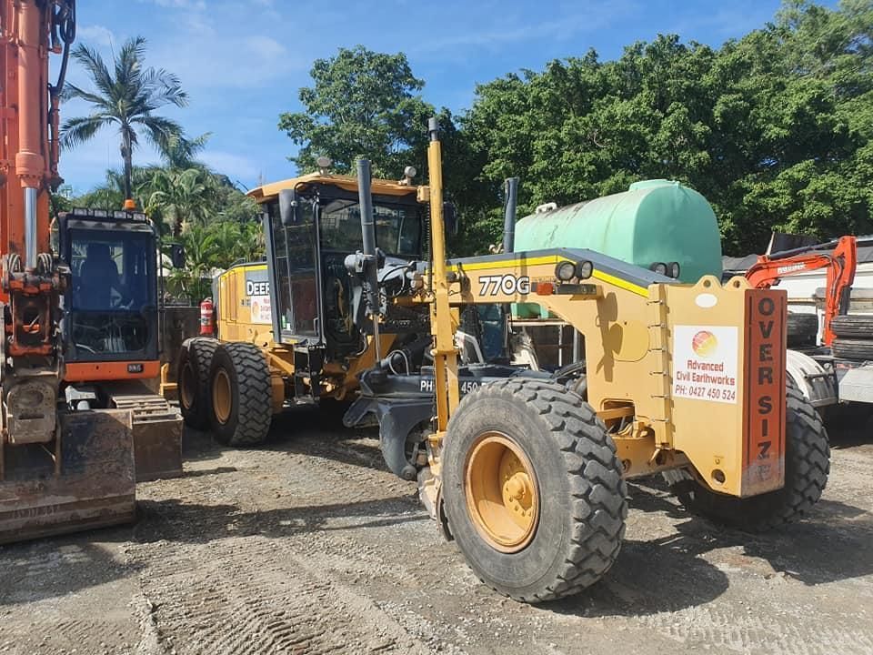 A Yellow Tractor With a Green Tank on the Back — Advanced Civil Earthworks In Port Douglas, QLD