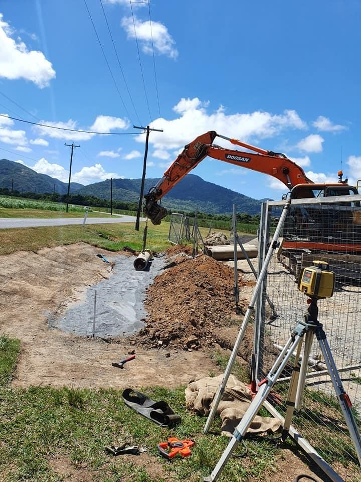 An Excavator is Digging a Hole in the Ground Next to a Tripod — Advanced Civil Earthworks In Port Douglas, QLD