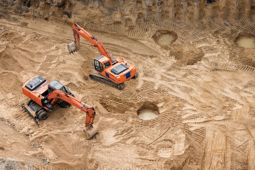 Two Excavators Are Working in a Dirt Field — Advanced Civil Earthworks In Kuranda, QLD