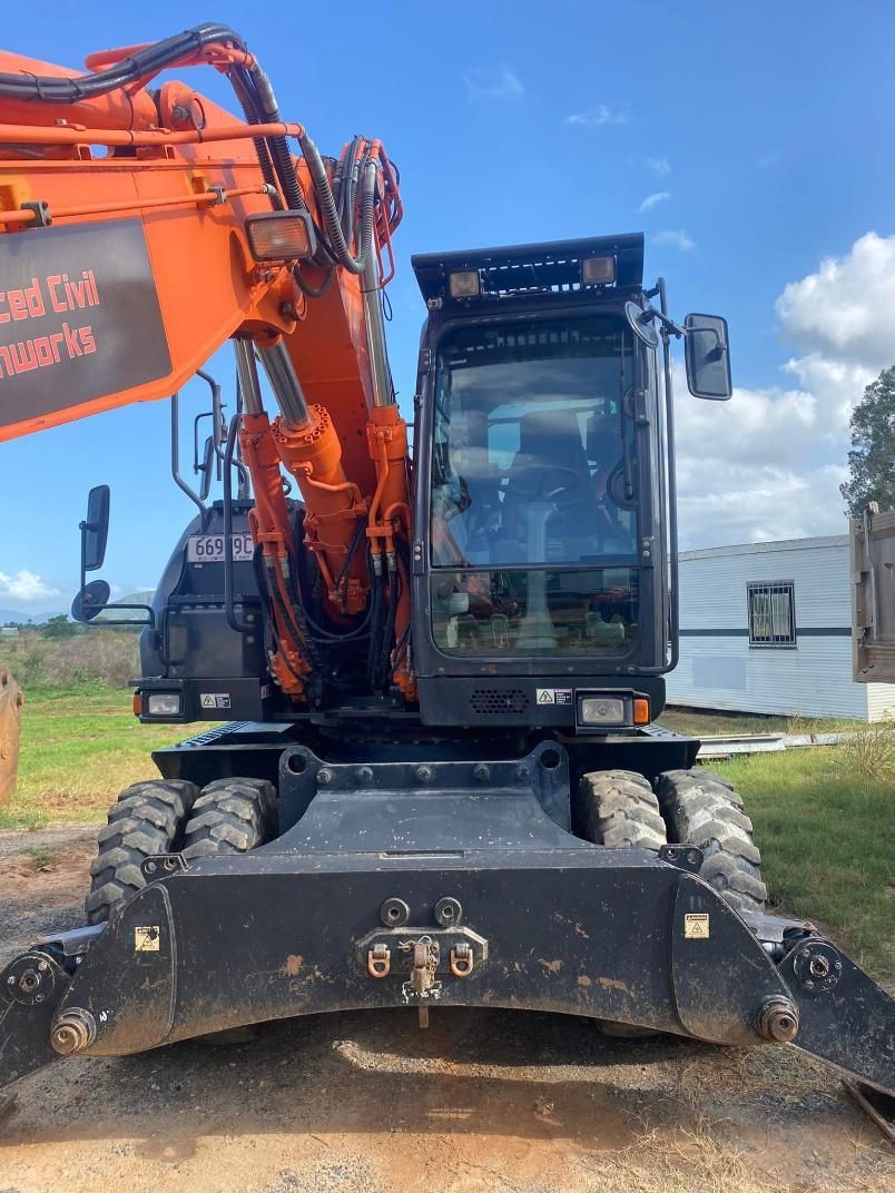 A Large Orange Excavator is Parked in a Dirt Field — Advanced Civil Earthworks In Cooktown, QLD