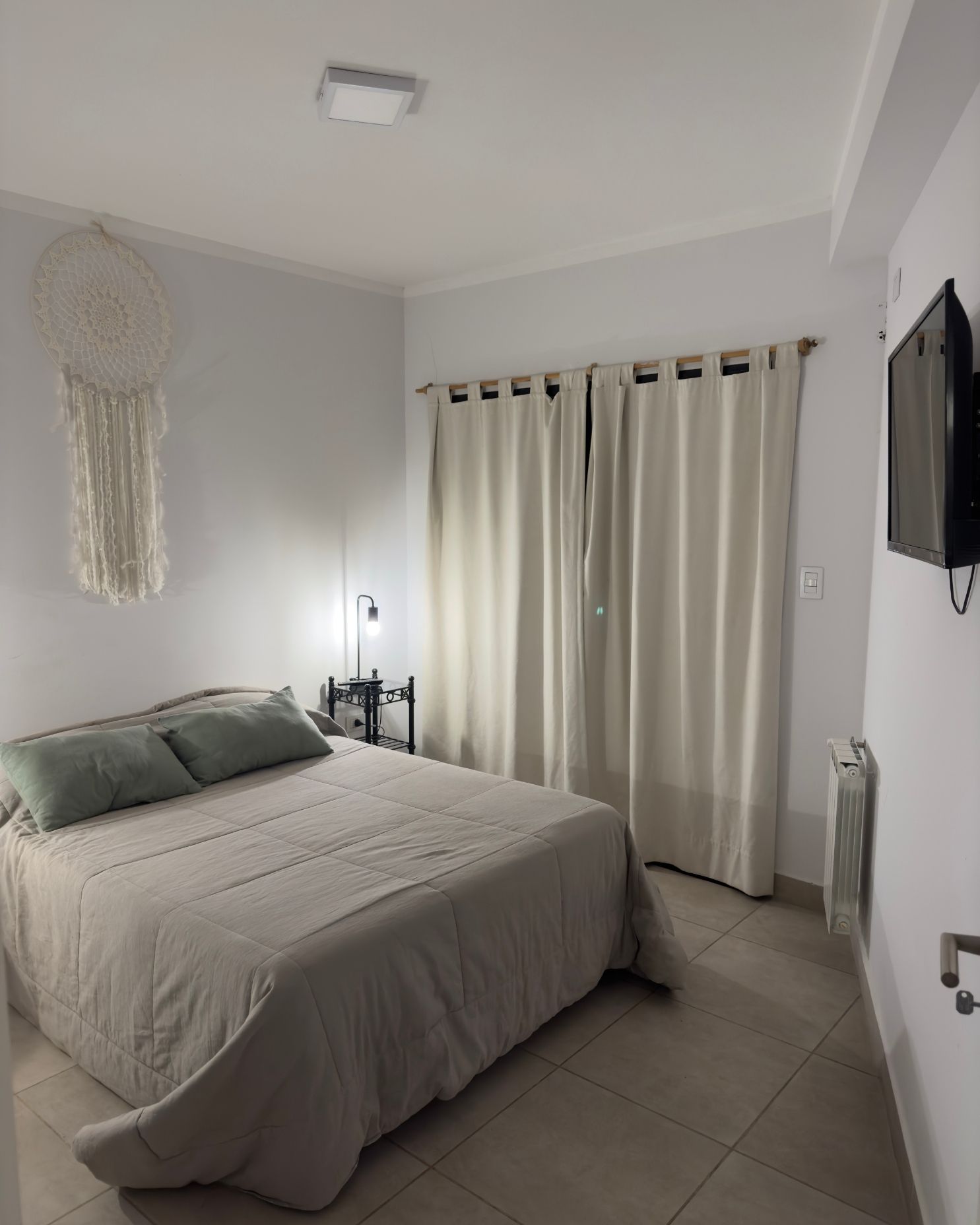 A bedroom with a bed and a television on the wall.