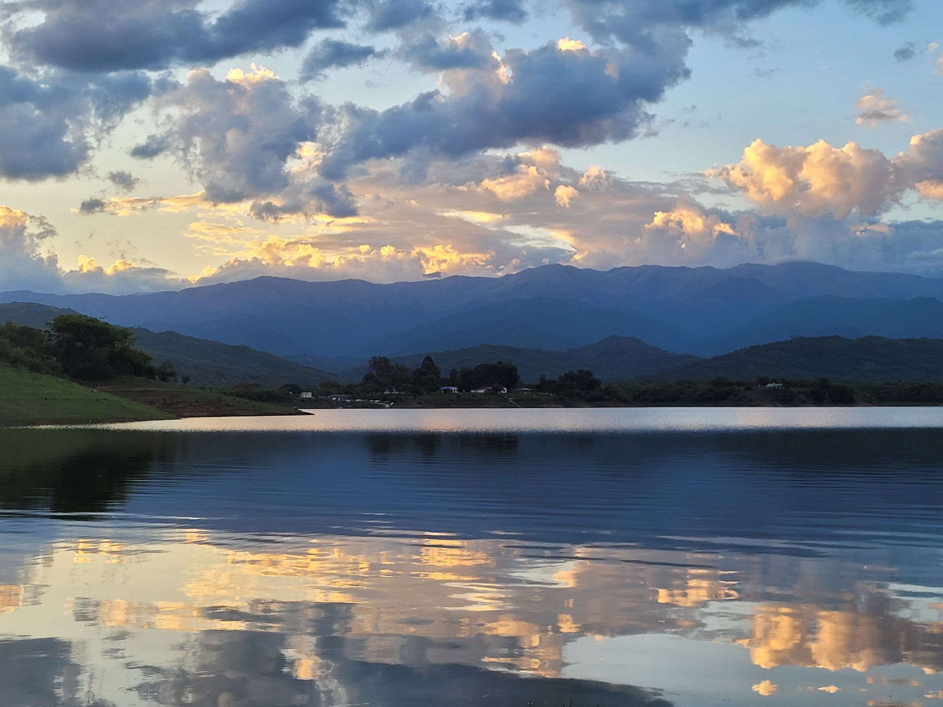 A lake with mountains in the background and clouds reflected in the water