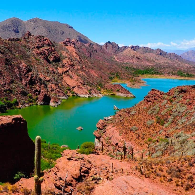 A lake in the middle of a desert with mountains in the background