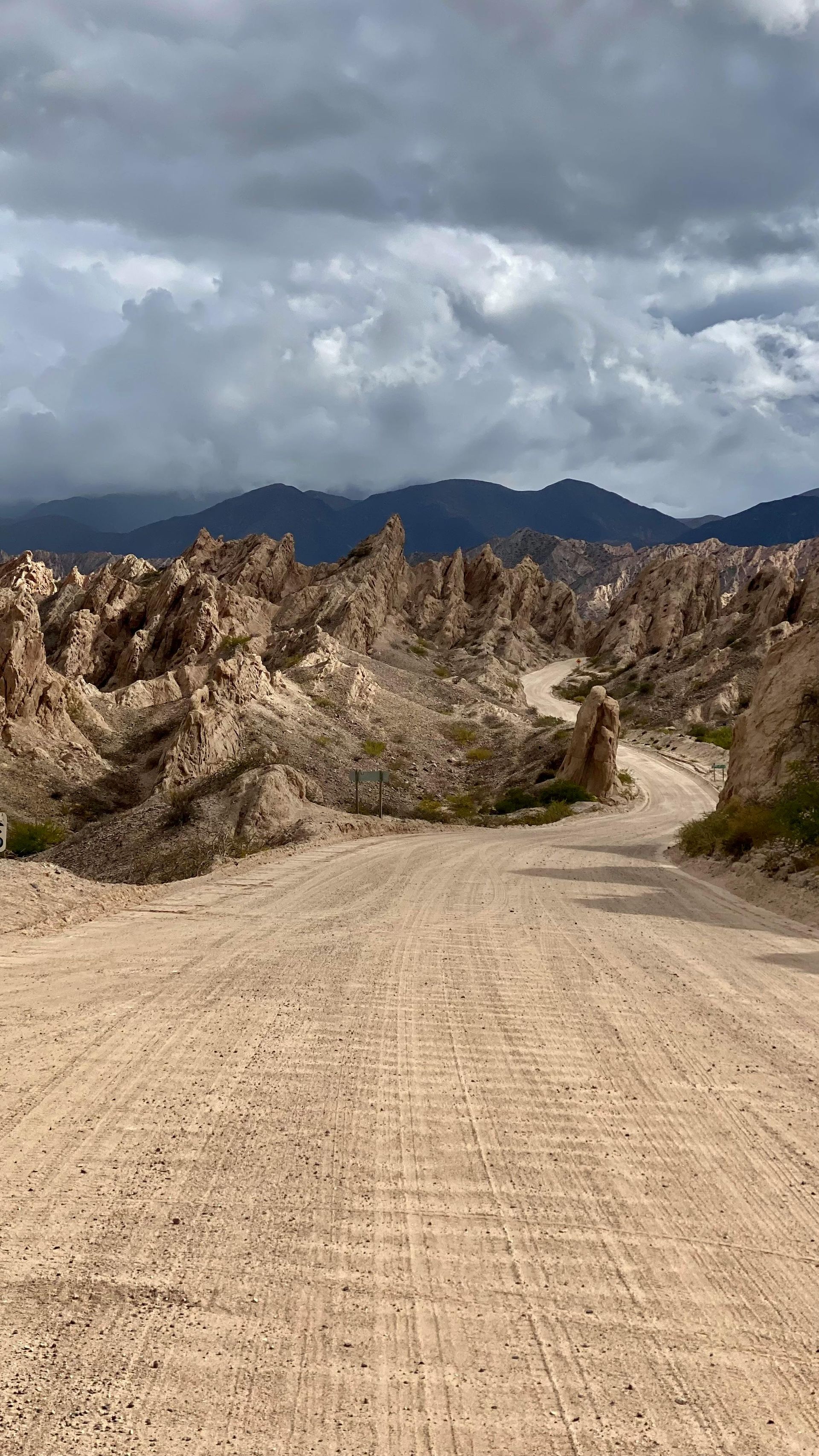 A dirt road in the desert with mountains in the background.