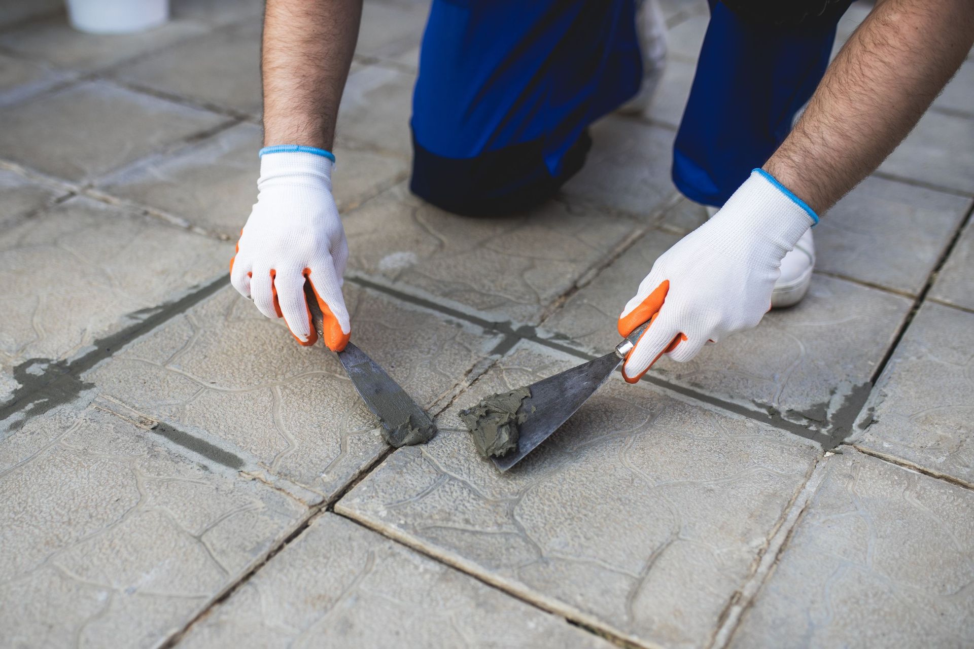 man repairing grout on tile floor