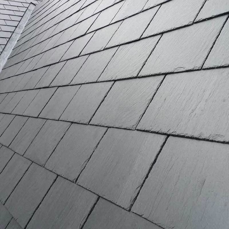 Close-up of gray roof shingles arranged in staggered rows, viewed at an angle.