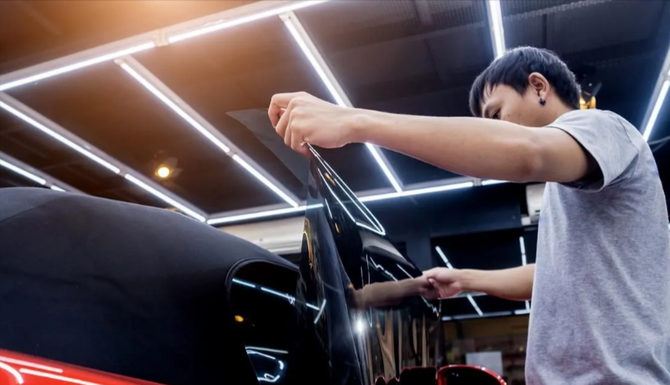 Professional car window tint installation in a garage.