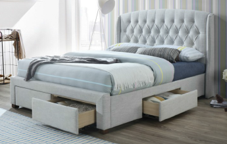 a white upholstered bed with drawers underneath it in a bedroom.