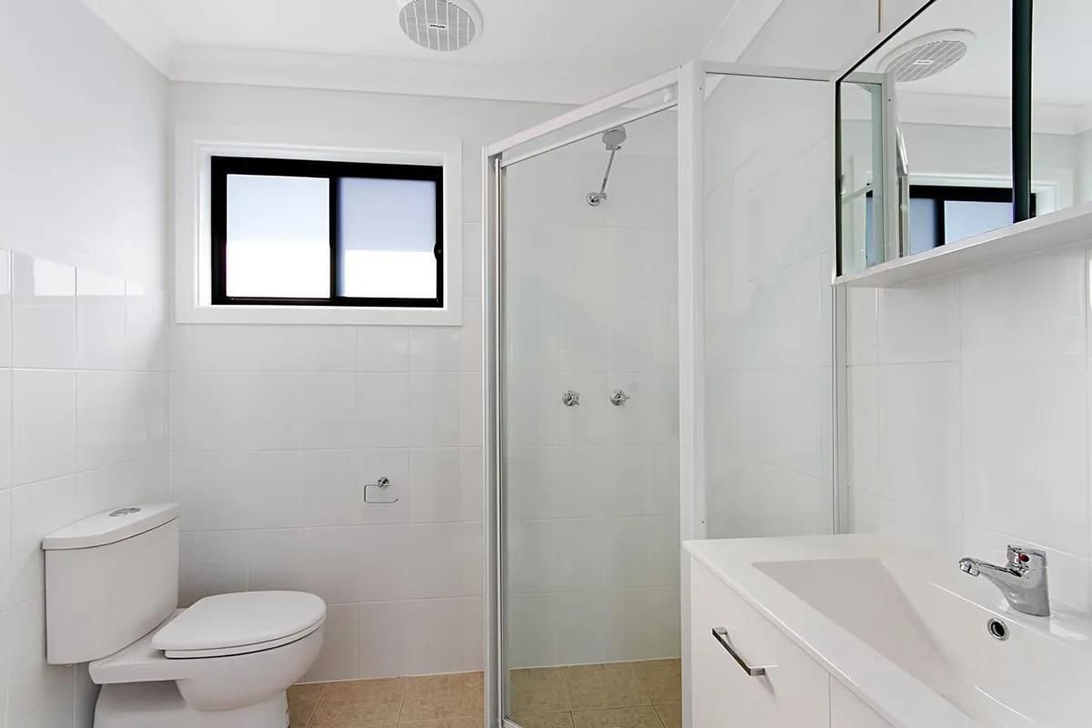 A Bathroom with A Toilet, Sink, Shower and Window — Peter Whelan Building Services in Wyoming, NSW