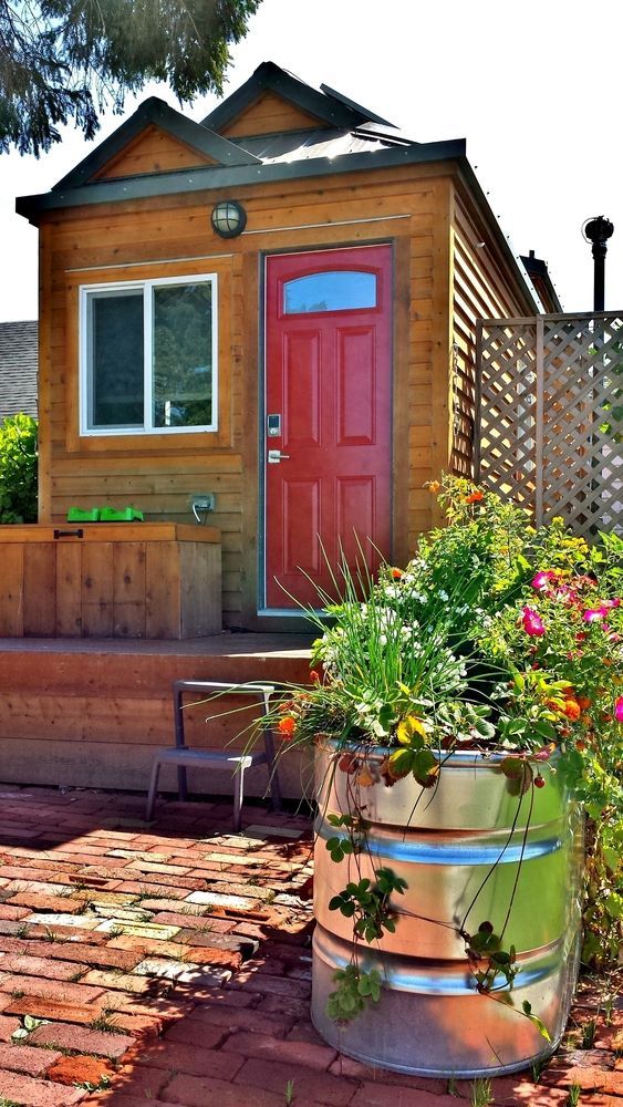 Small Wooden Cabin With Red Door, Window, and Flower Barrel — Peter Whelan Building Services in Wyoming, NSW
