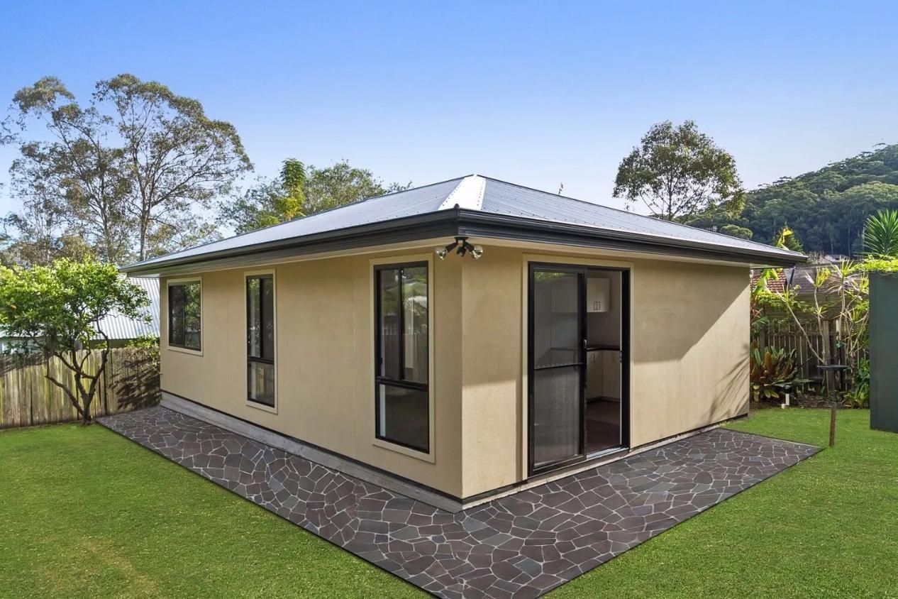 A newly renovated yellow house surrounded by freshly placed grass.