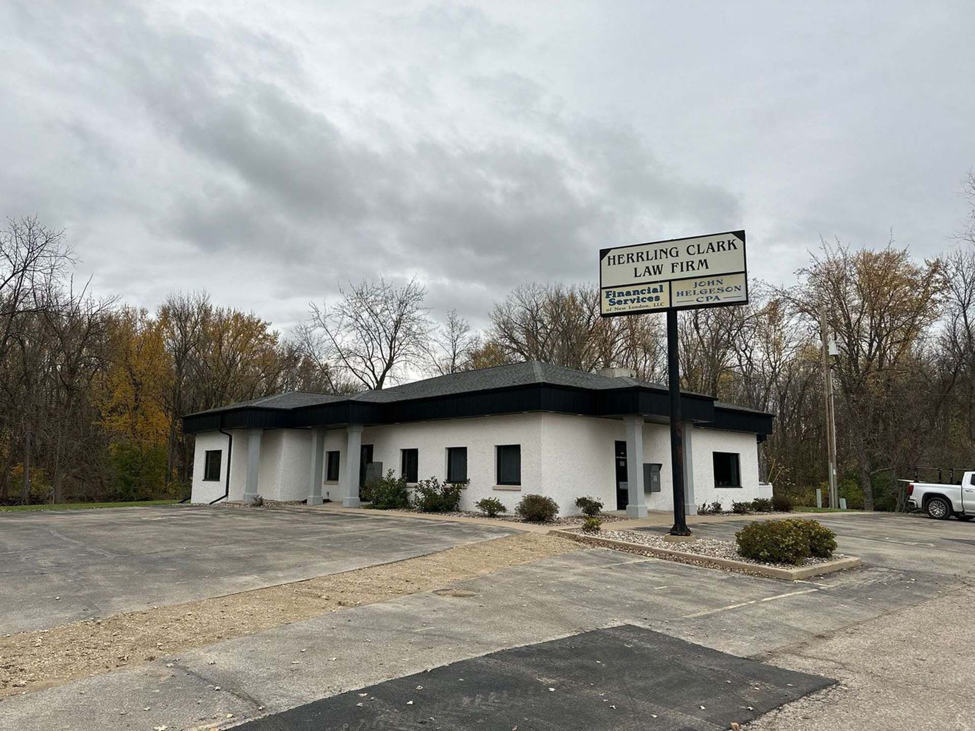 A white building with a sign on top of it in a parking lot.