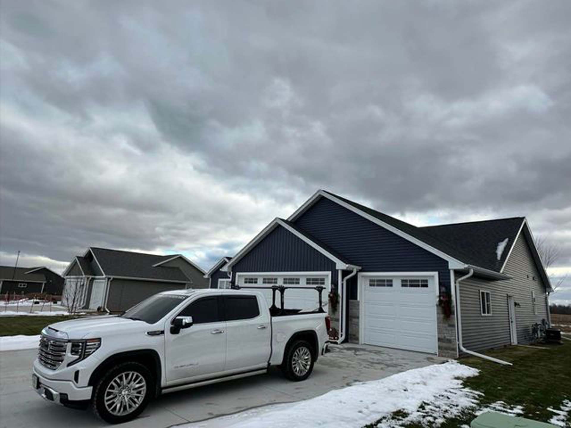 A white truck is parked in front of a house.
