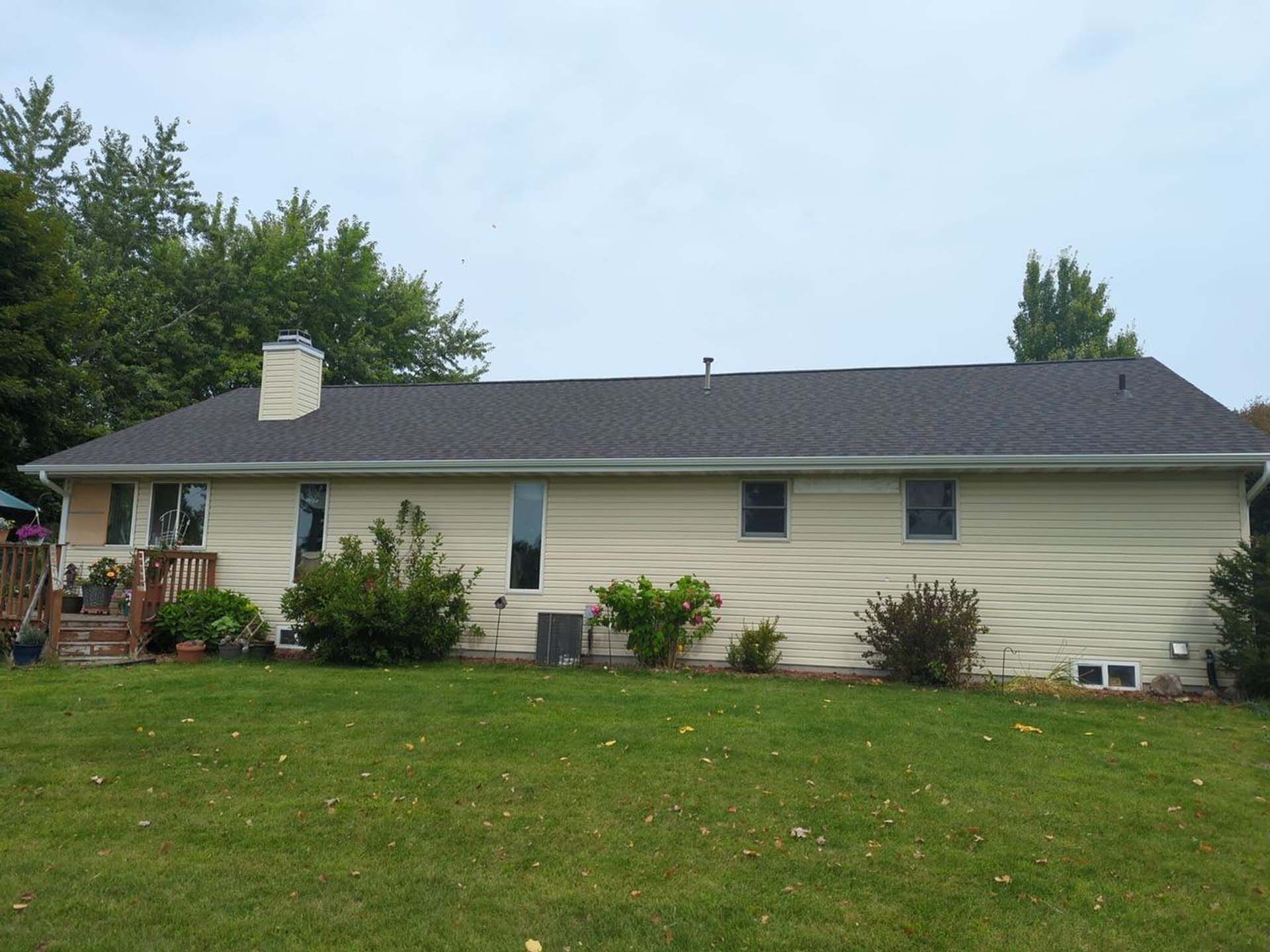 A white house with a black roof and a deck