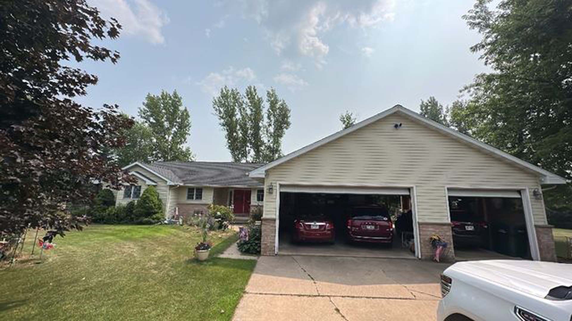 A white truck is parked in front of a house with two cars in the garage.