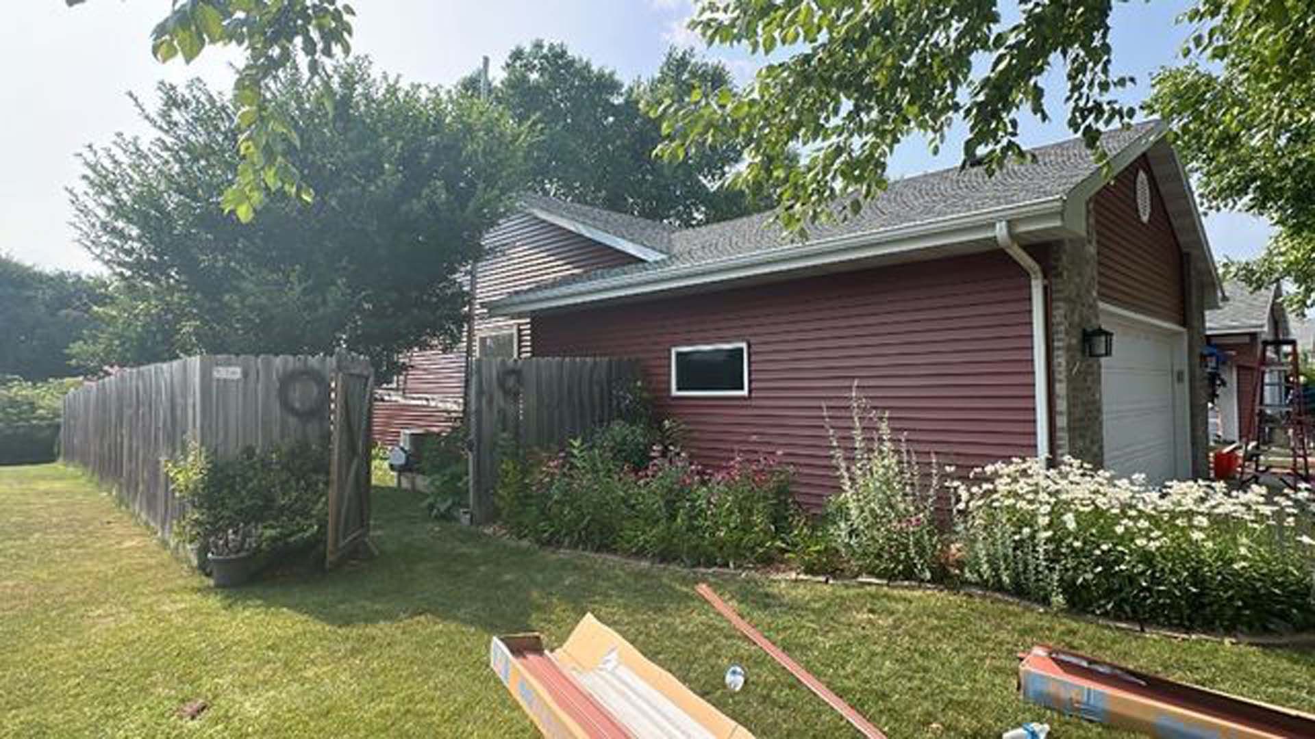 A house with a red siding and a fence in the backyard.