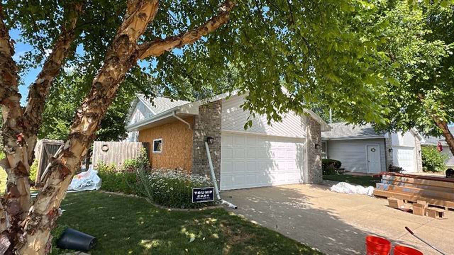 A house with a garage and a tree in front of it.