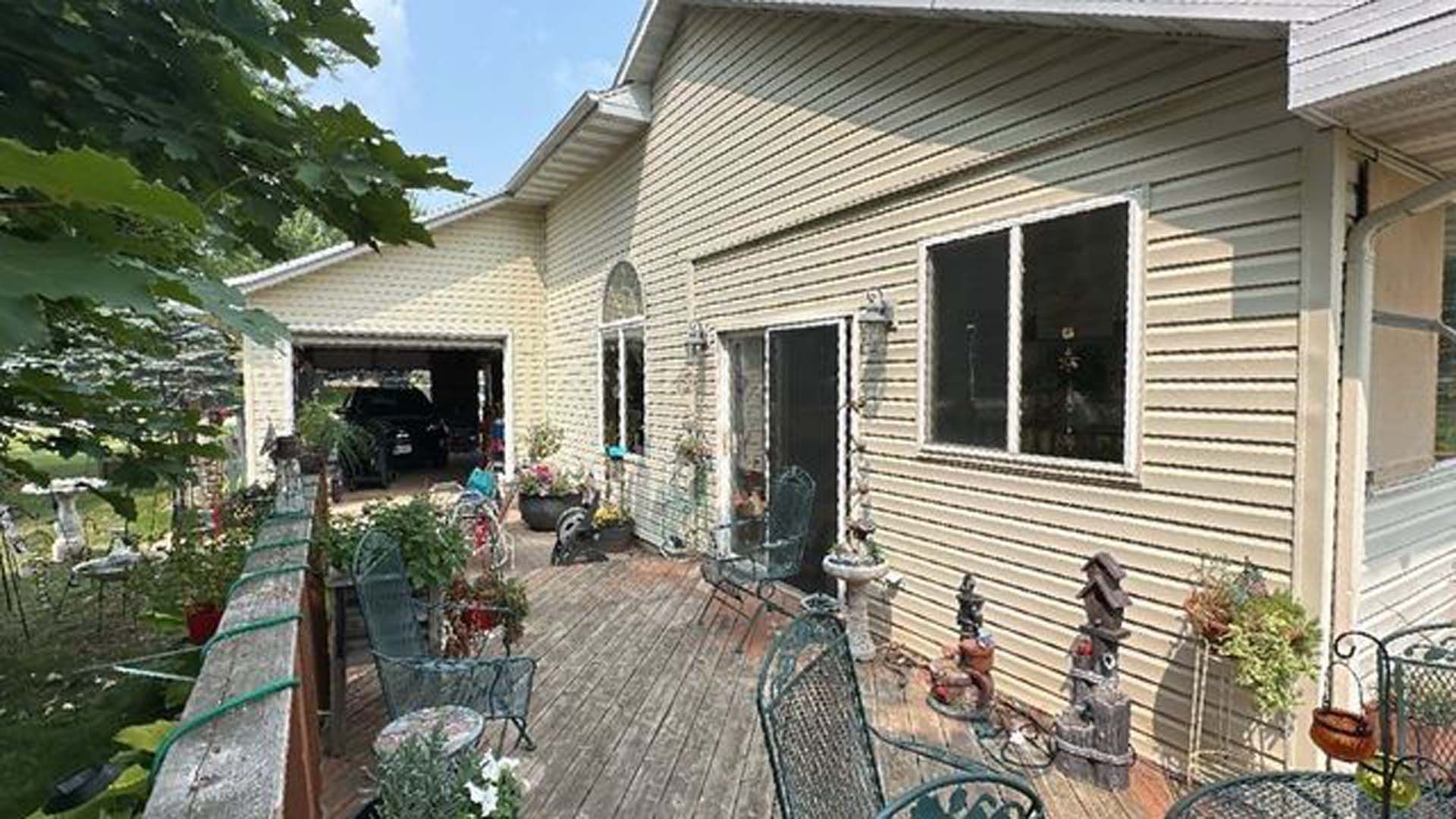 A large house with a large deck with tables and chairs on it.