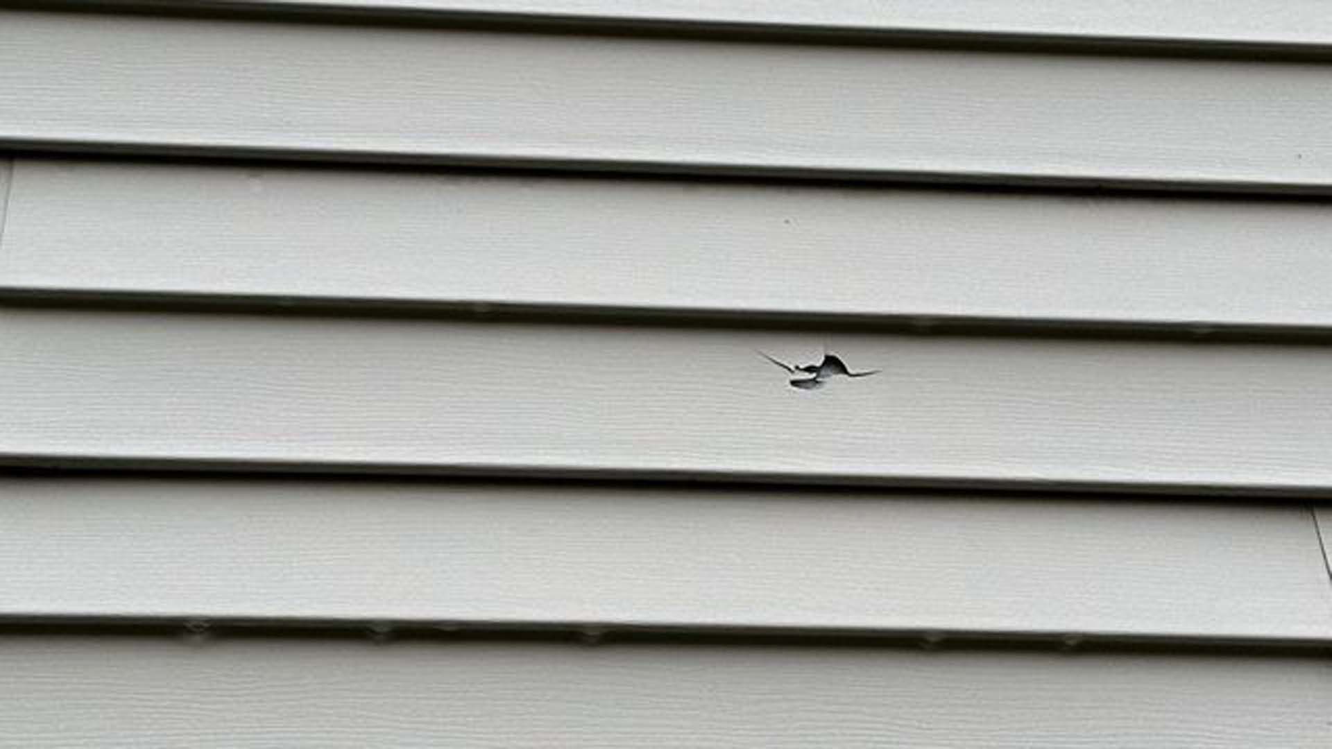 A close up of a white siding with a hole in it