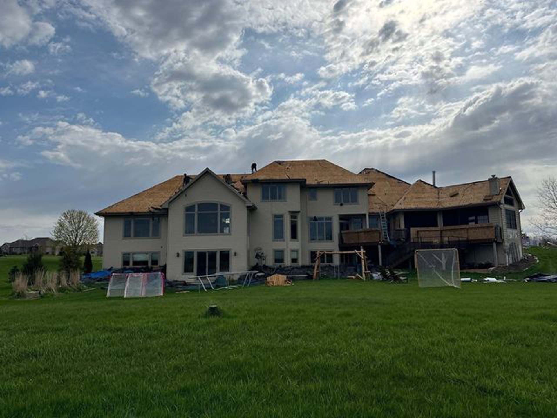 A large house is sitting on top of a lush green field.