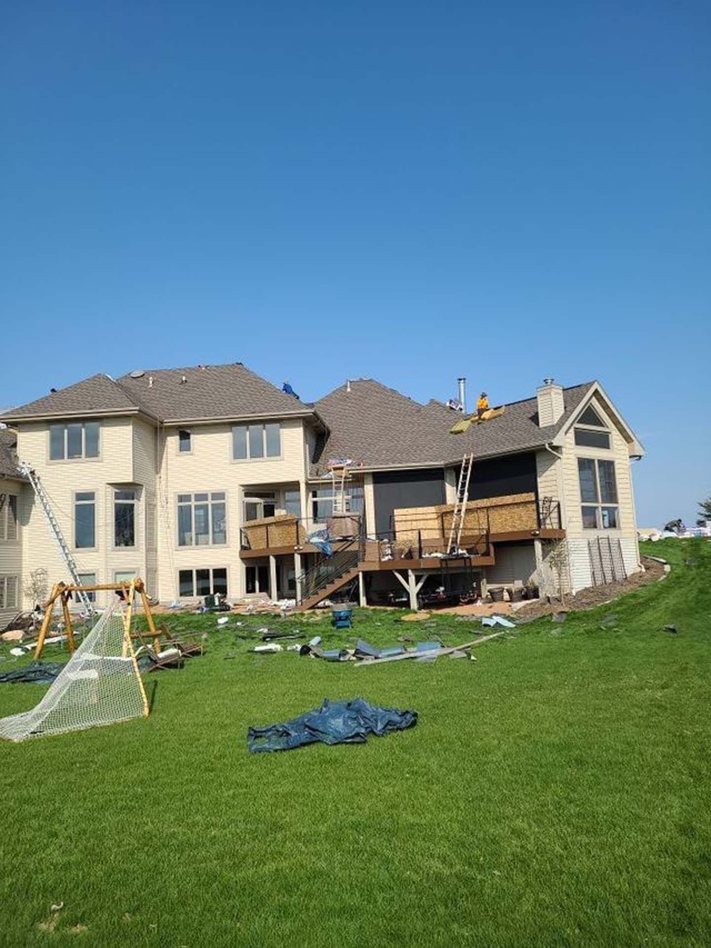 A large house is being painted in a backyard.
