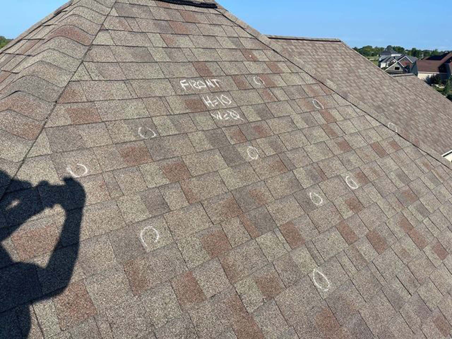A person is standing on top of a roof with a shadow on it.