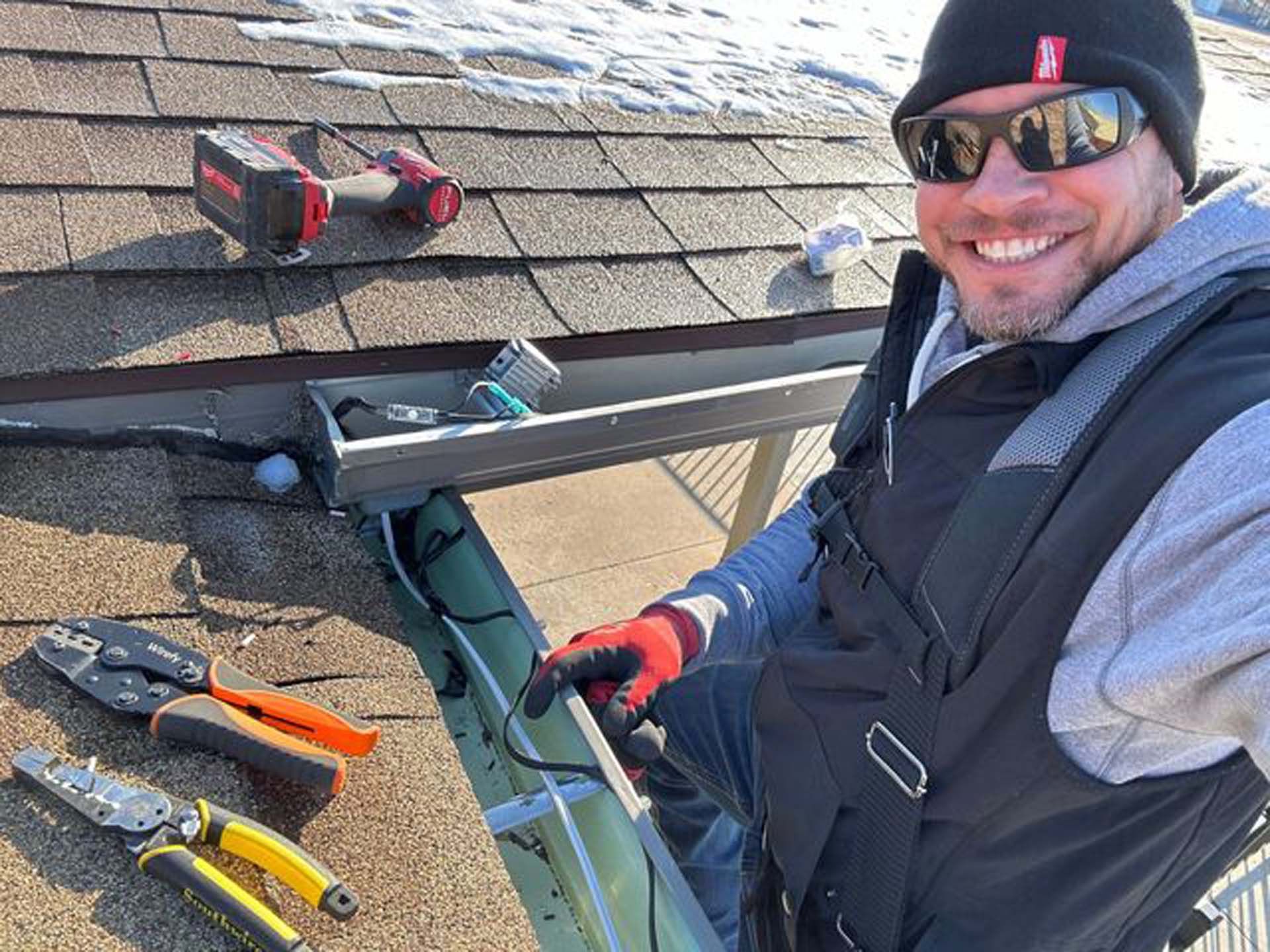 A man wearing sunglasses and a hat is working on a roof.