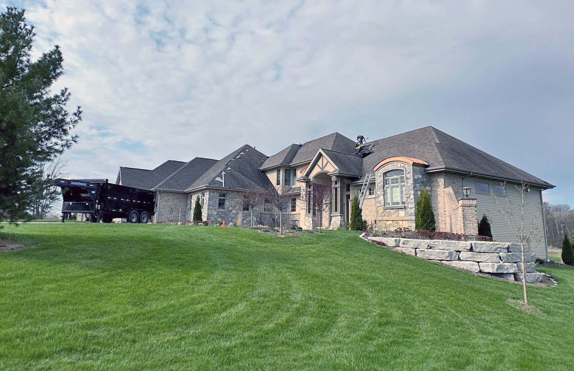 A large house is sitting on top of a lush green hill.