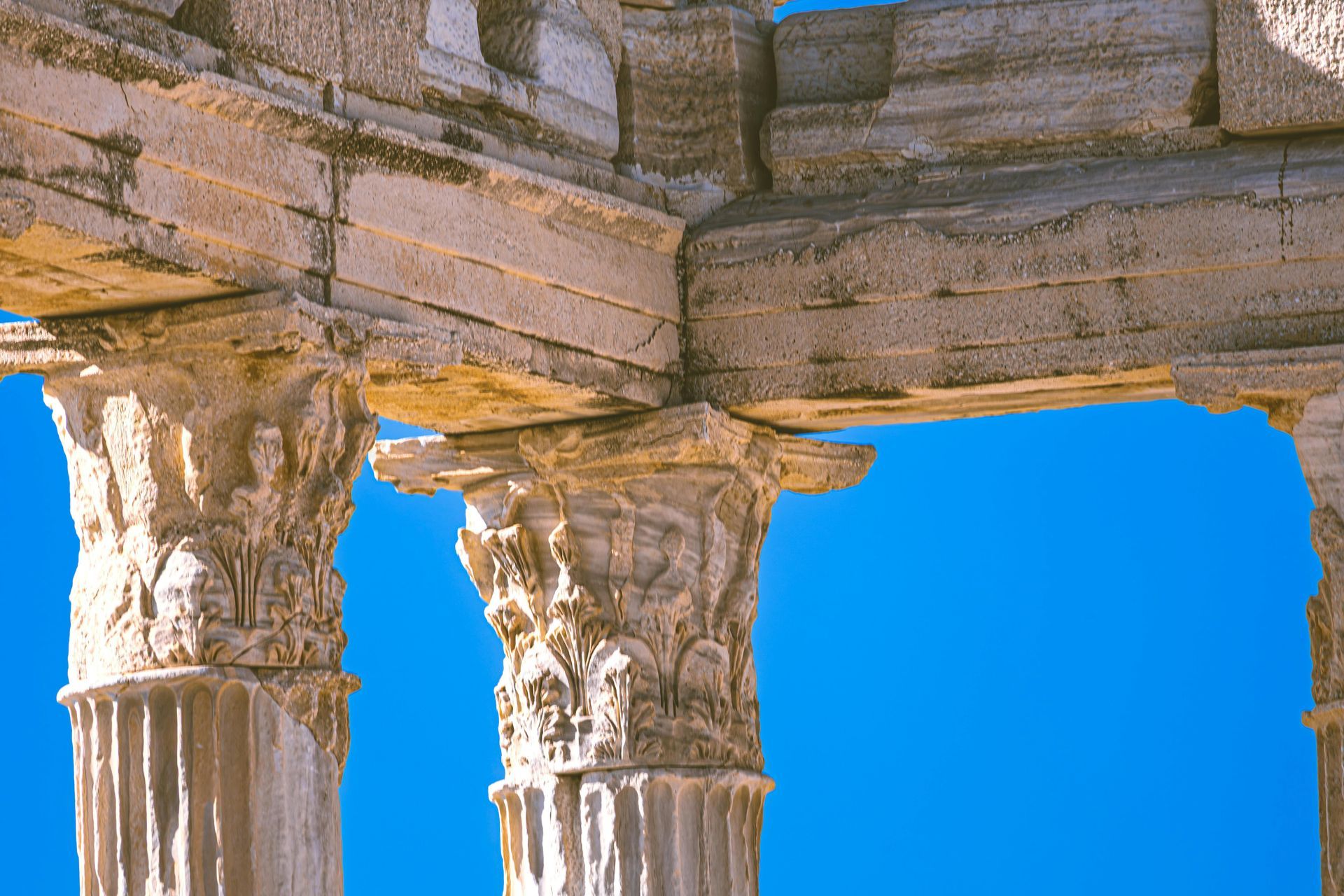 Ancient stone columns with ornate capitals against a bright blue sky