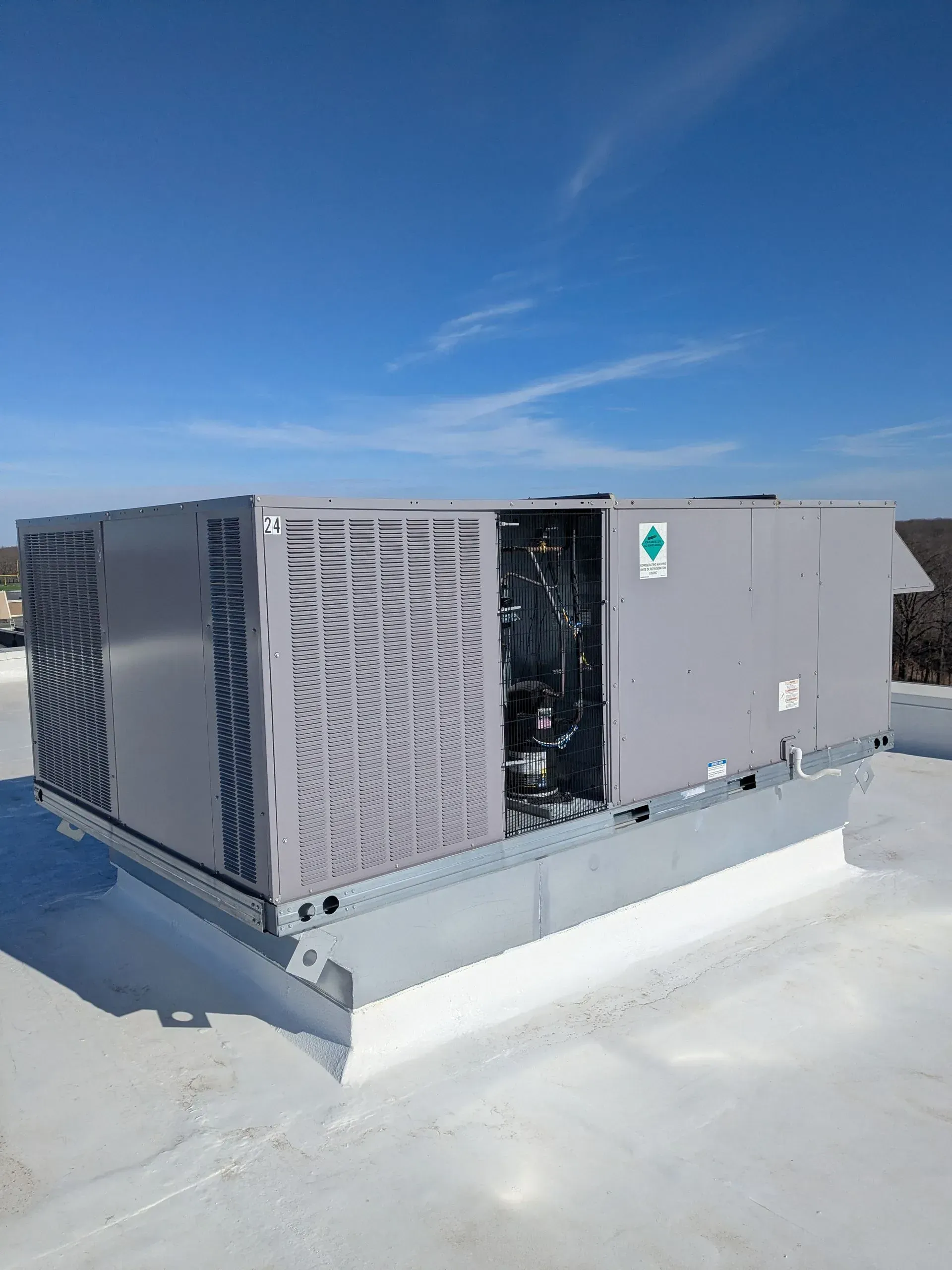 Gray air conditioning unit mounted on a brick wall, with power cable and conduit.
