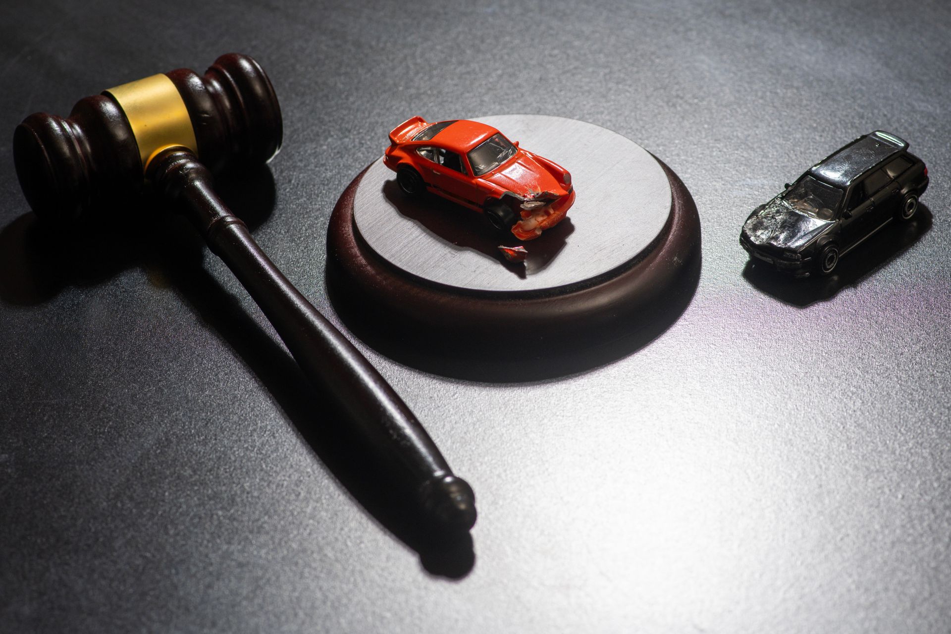 Legal gavel next to crashed toy cars for a car accident injury lawyer representing vehicle claims.