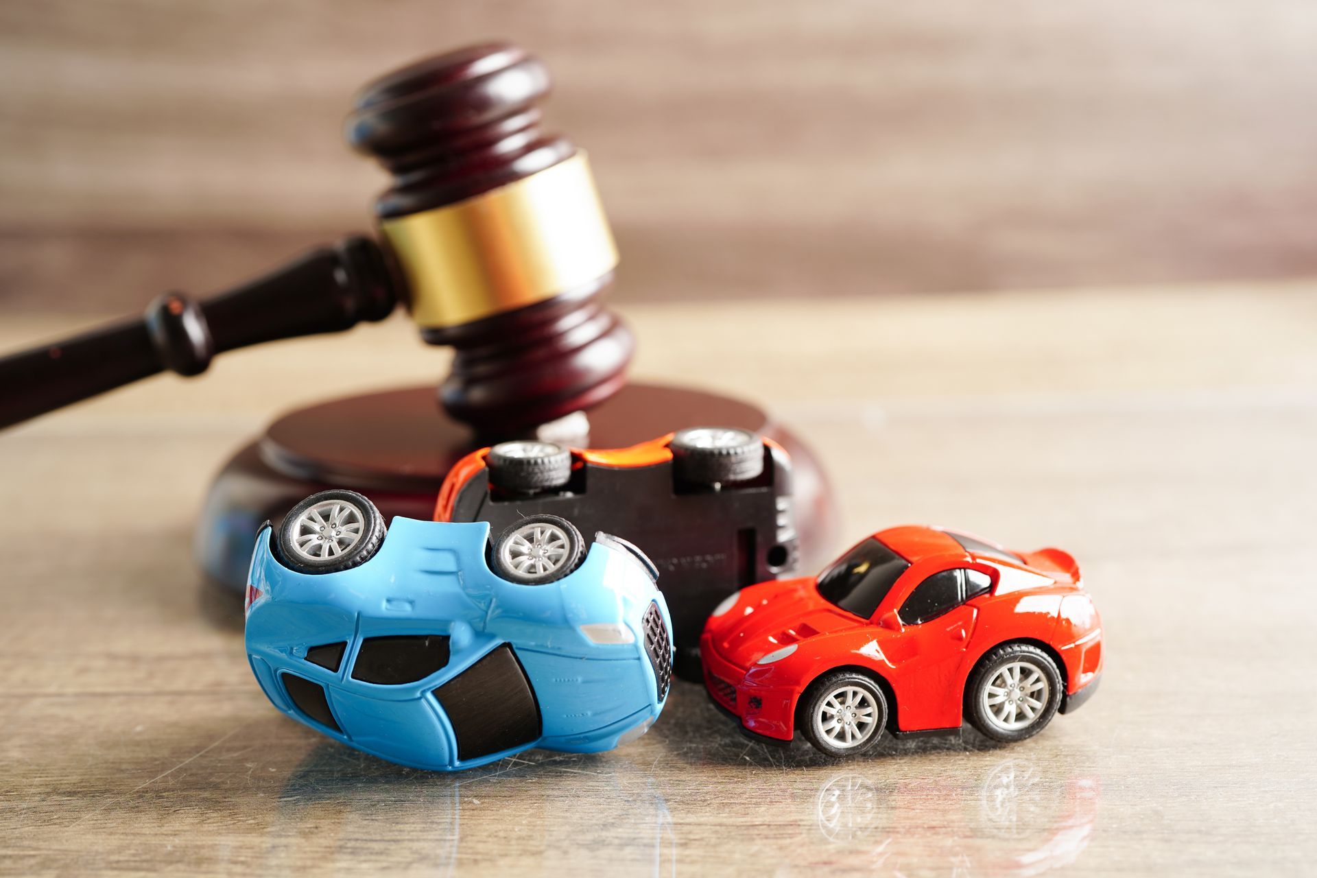 Toy cars in a crash scene beside a judge’s gavel, symbolizing car accident law and legal consequence