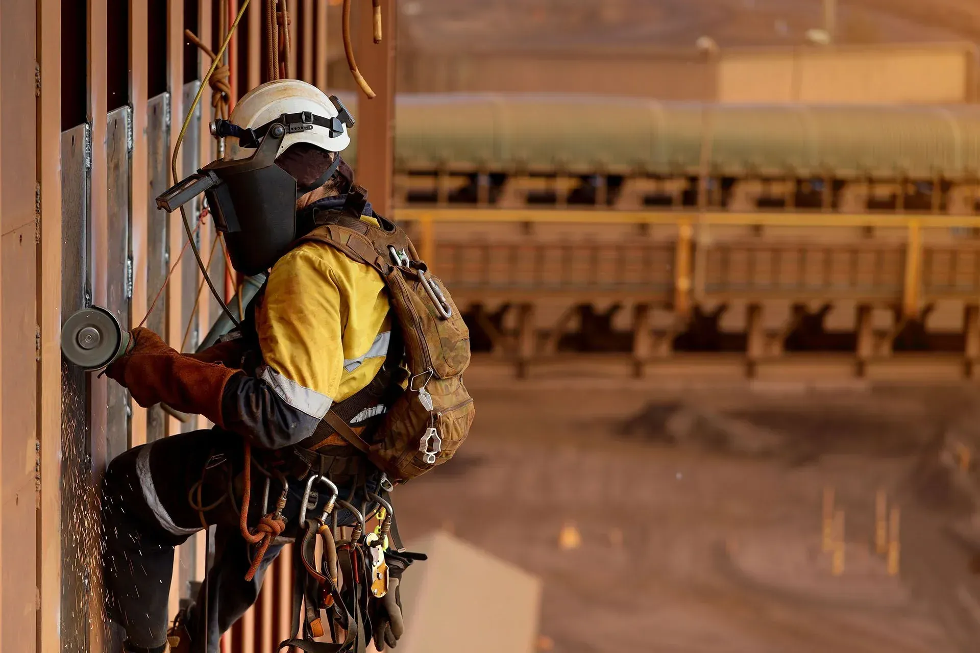 A rope access specialist wearing a helmet and safety gear is working at heights