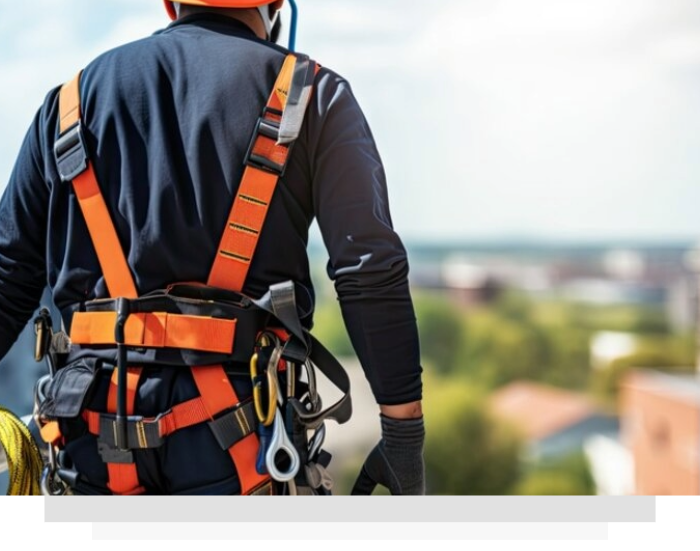 Worker in orange safety harness standing on a rooftop with cityscape in the background