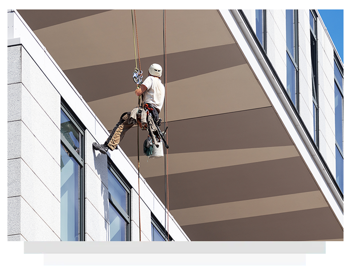 A man is climbing a building with a rope attached to him.