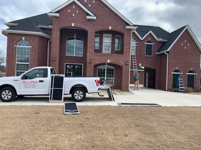 A white truck is parked in front of a large brick house.