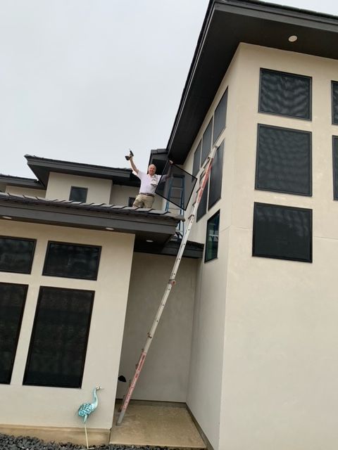A man is standing on the roof of a building with a ladder
